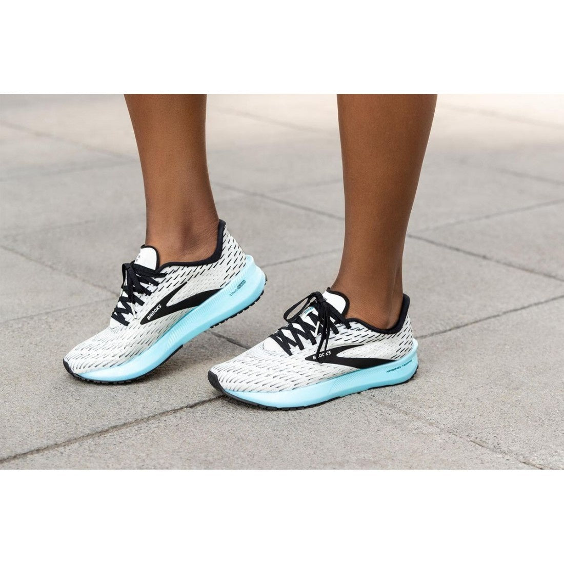 woman wearing brooks hyperion tempo in white and black with blue sole