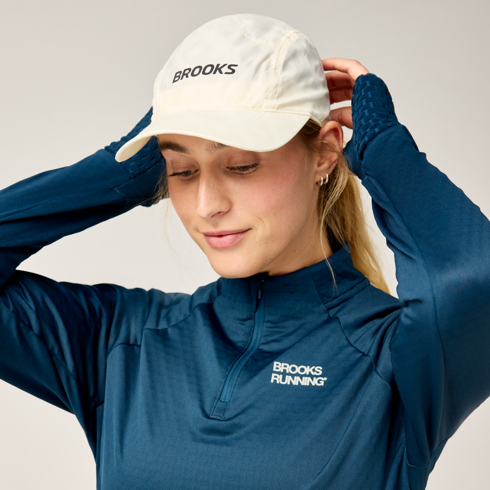 brooks journey reflective hat, lightweight sweat wicking reflective running hat, white colour with reflective silver logo, woman wearing running hat