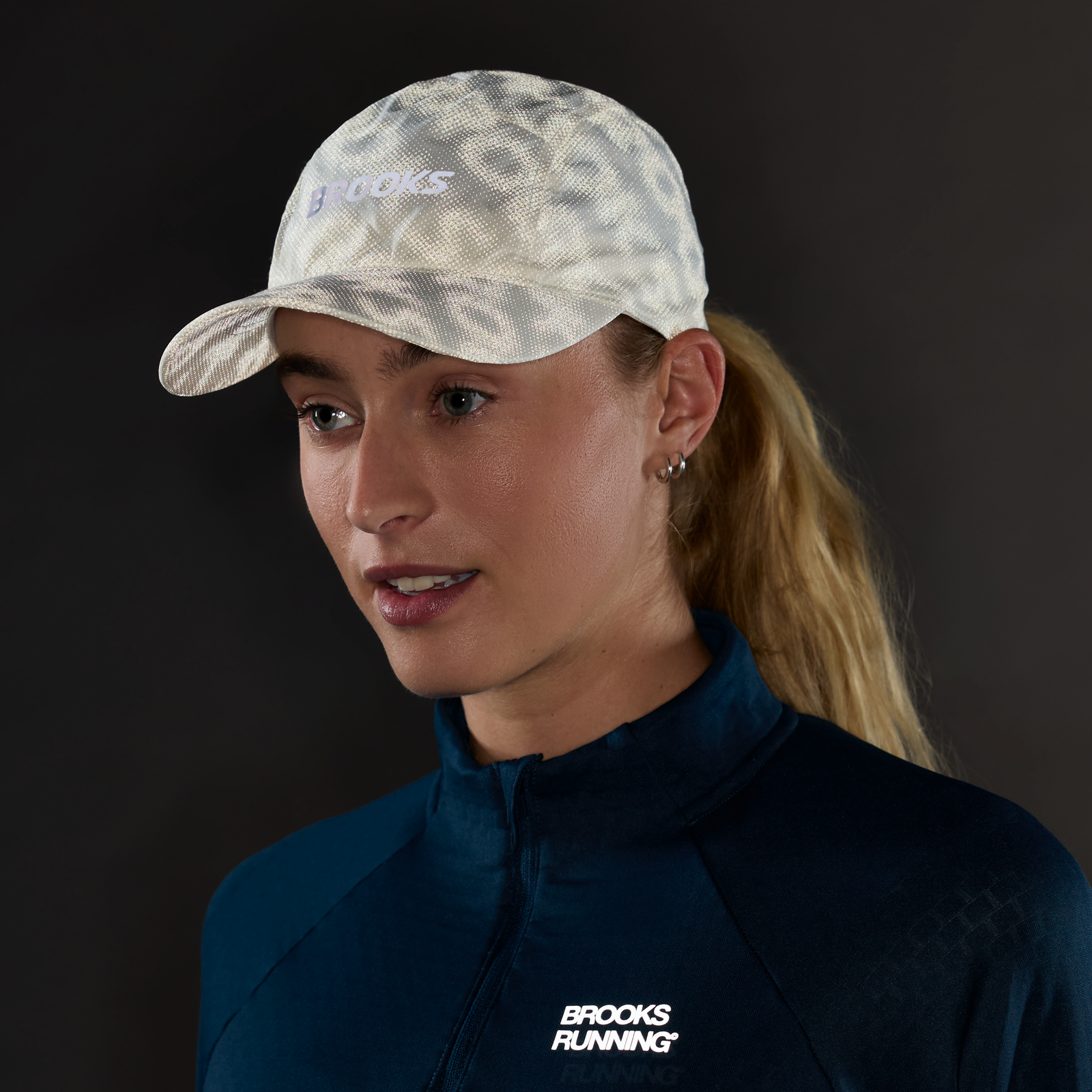 brooks journey reflective hat, lightweight sweat wicking reflective running hat, white colour with reflective silver logo, woman wearing running hat in dark with reflective hat pattern