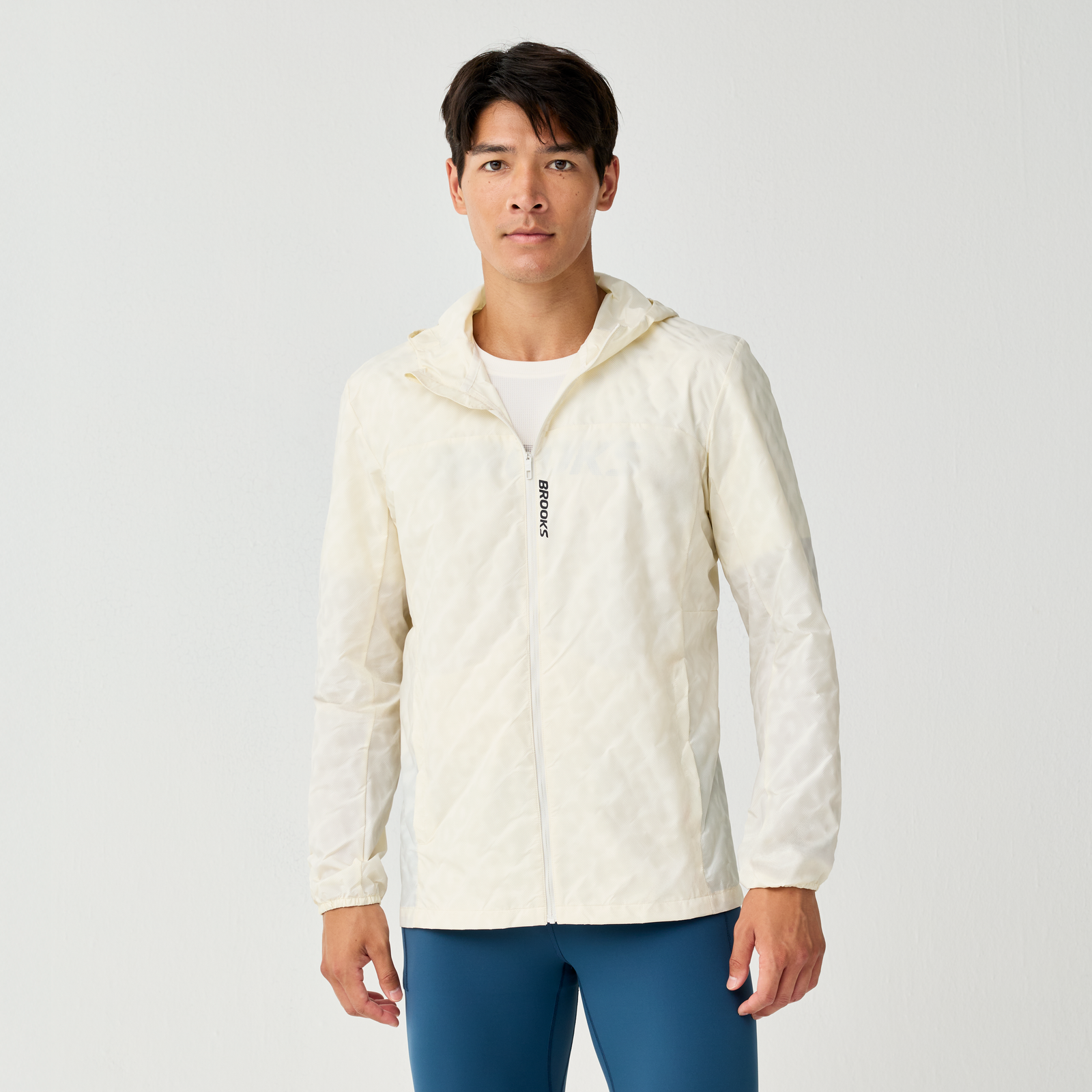 Man wearing Brooks Canopy Reflective Run Jacket, white colour, reflective details, showing the front with zip and brooks logo