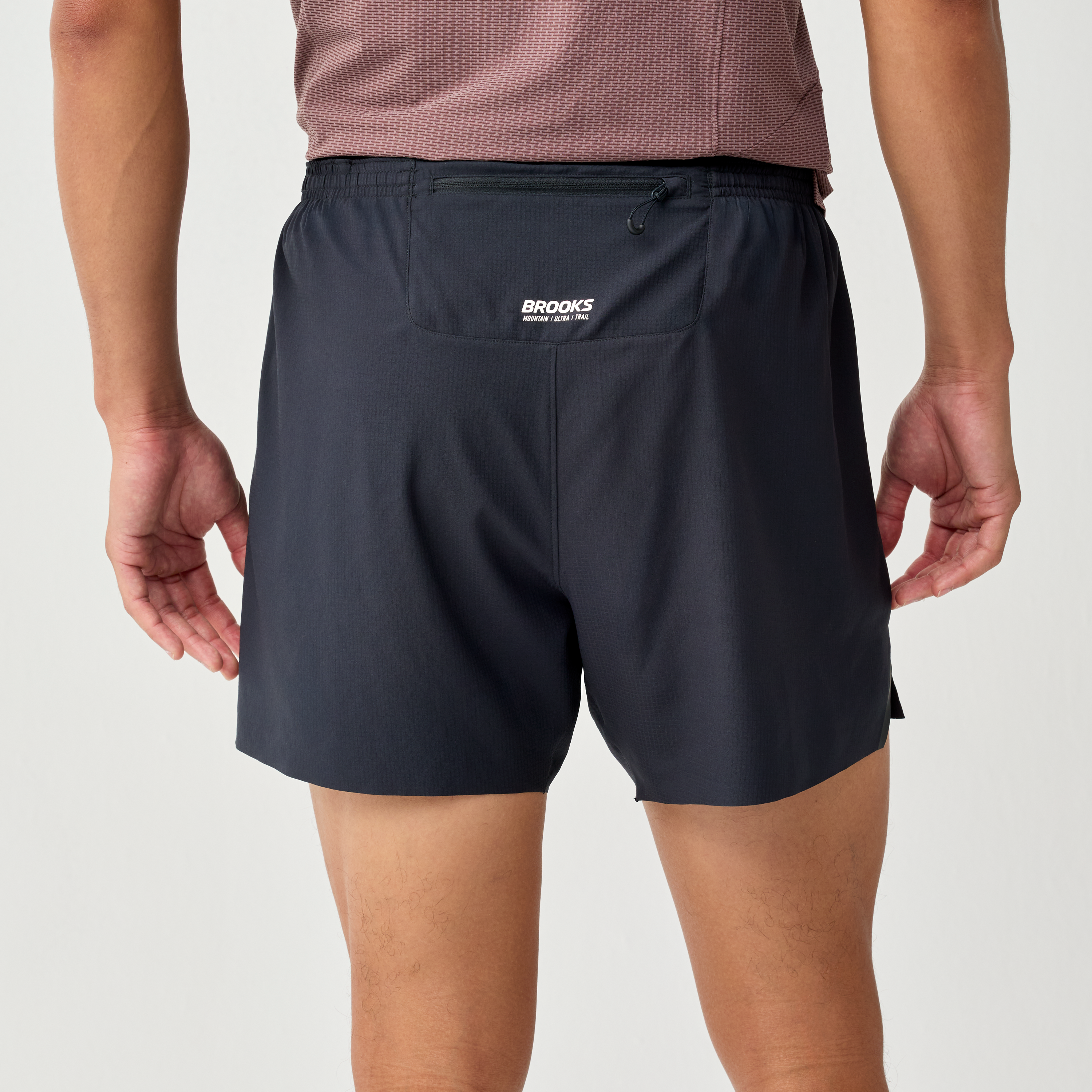 brooks cascadia short for men, running short with pocket storage belt, black colour with white brooks logo, back of man wearing shorts waist down