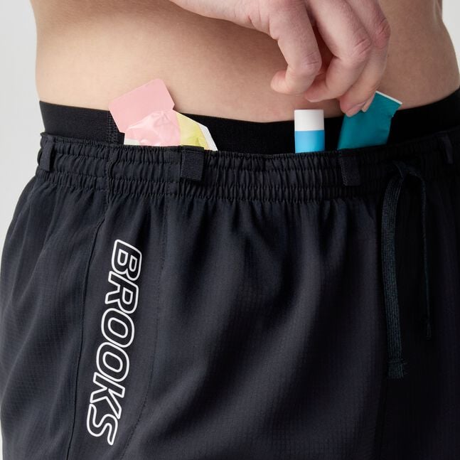 woman wearing brooks cascadia running short, lightweight women's trail-running shorts, black with white logo, close up of short
