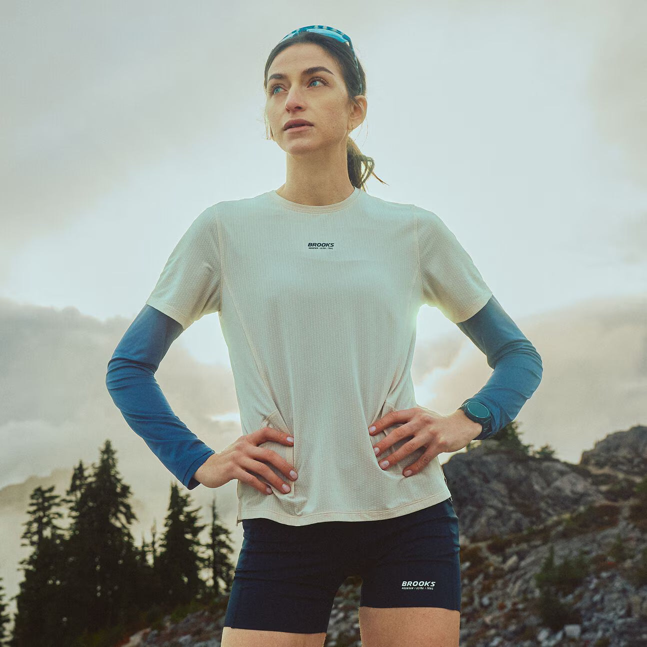 brooks cascadia short tight, 6" fitted running shorts for women, black colour, profile of woman wearing brooks short on a scenic trail background
