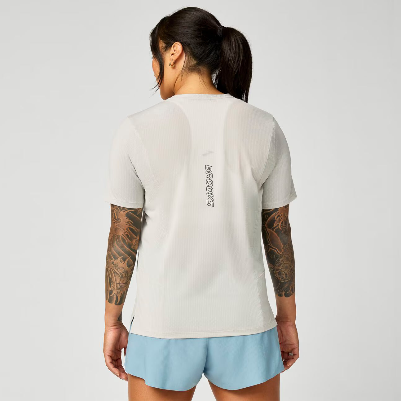 brooks womens high point short sleeve 2.0, super lightweight and breathable trail running top, grey blue colour, back view of a woman wearing brooks top with grey background