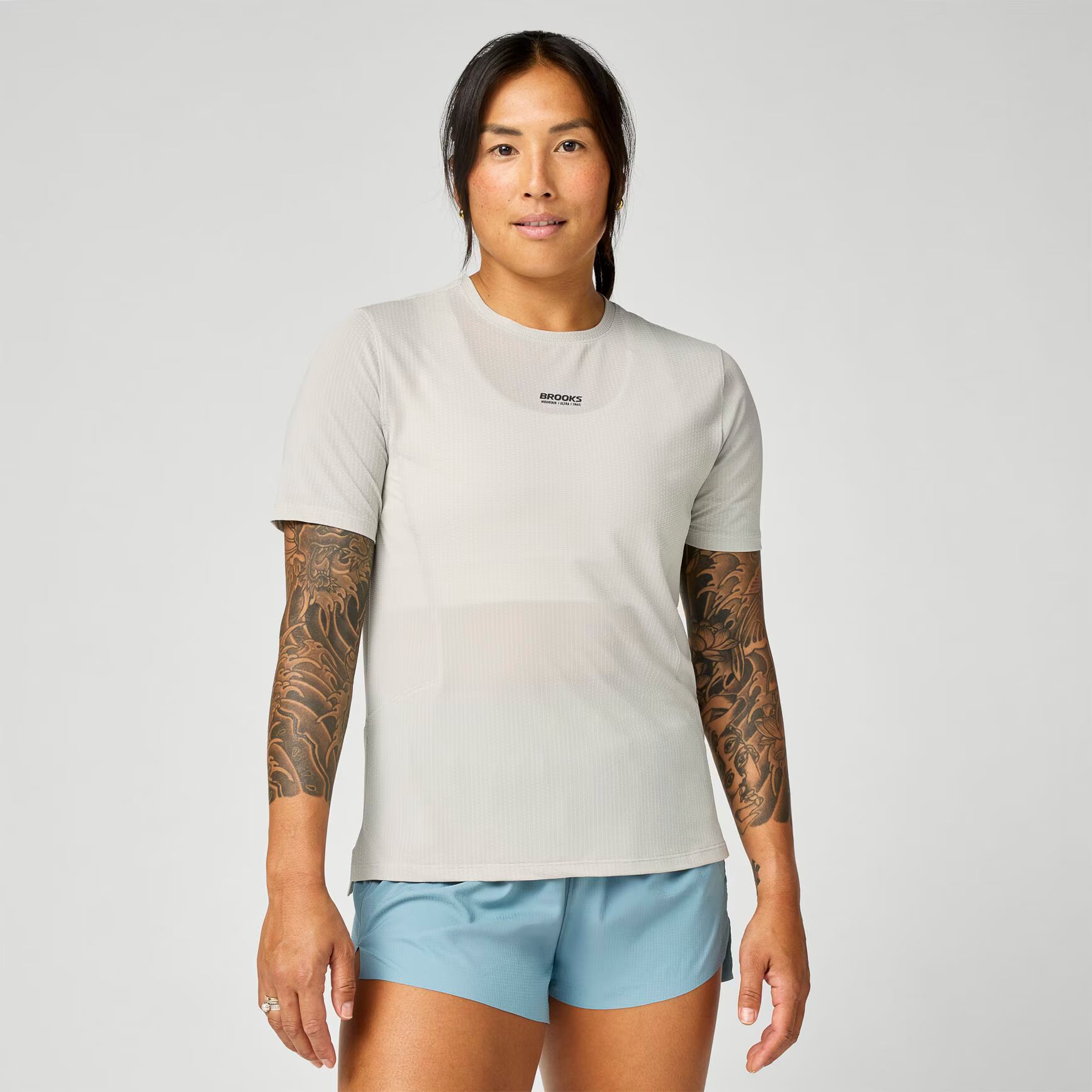 brooks womens high point short sleeve 2.0, super lightweight and breathable trail running top, grey blue colour, woman wearing brooks top with grey background