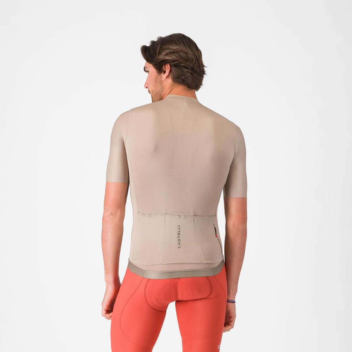 man showing back of castelli espresso 2 jersey, showing logo on back pockets, clay colour