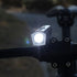 A close-up of a black Cateye AMPP 200 II bicycle headlight turned on in the dark