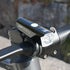 A close-up of a black Cateye AMPP 200 II bicycle headlight on handlebars
