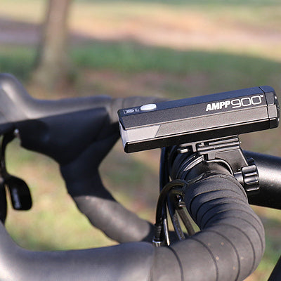 Bicycle handlebar with AMPP 900 bike light attached, blurred natural background