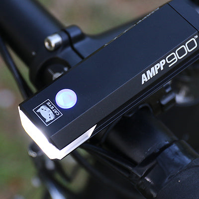 Bicycle light with 'AMPP 900' branding on a blurred background