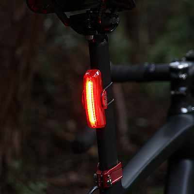 Red Cateye X2 Kinetic bicycle tail light attached to a bike frame with a dark background