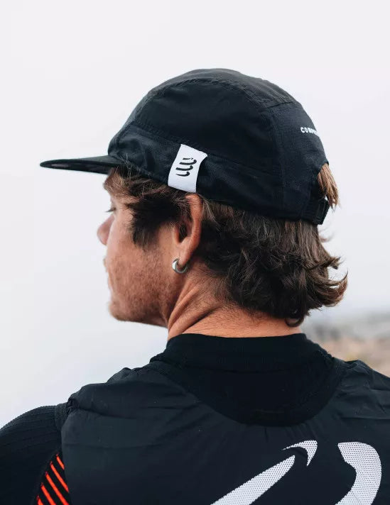Person wearing a black compressport 5 panel cap from behind