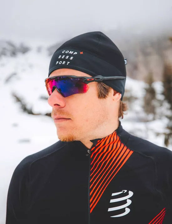 compressport hurricane beanie, warm moisture wicking hat, black colour, person wearing a compressport hat with red sunglasses