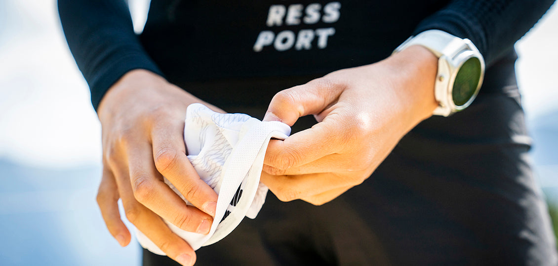 compressport ice cap sun shape, close up of person rolling up white running hat with neck protection