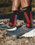 person wearing compressport pro racing trail socks, crew length compression trail running sock, red black colour with shoes