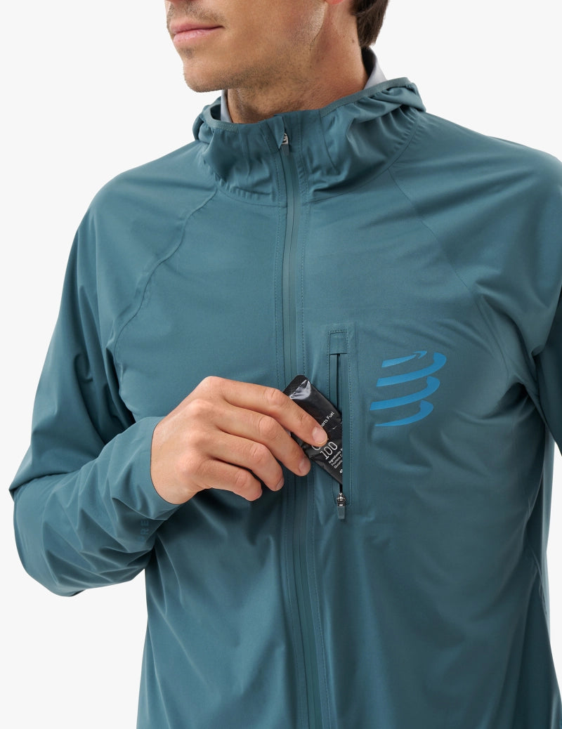 compressport tempest waterproof jacket, breathable and waterproof running jacket, deep aqua blue colour, close up of chest pocket zipper