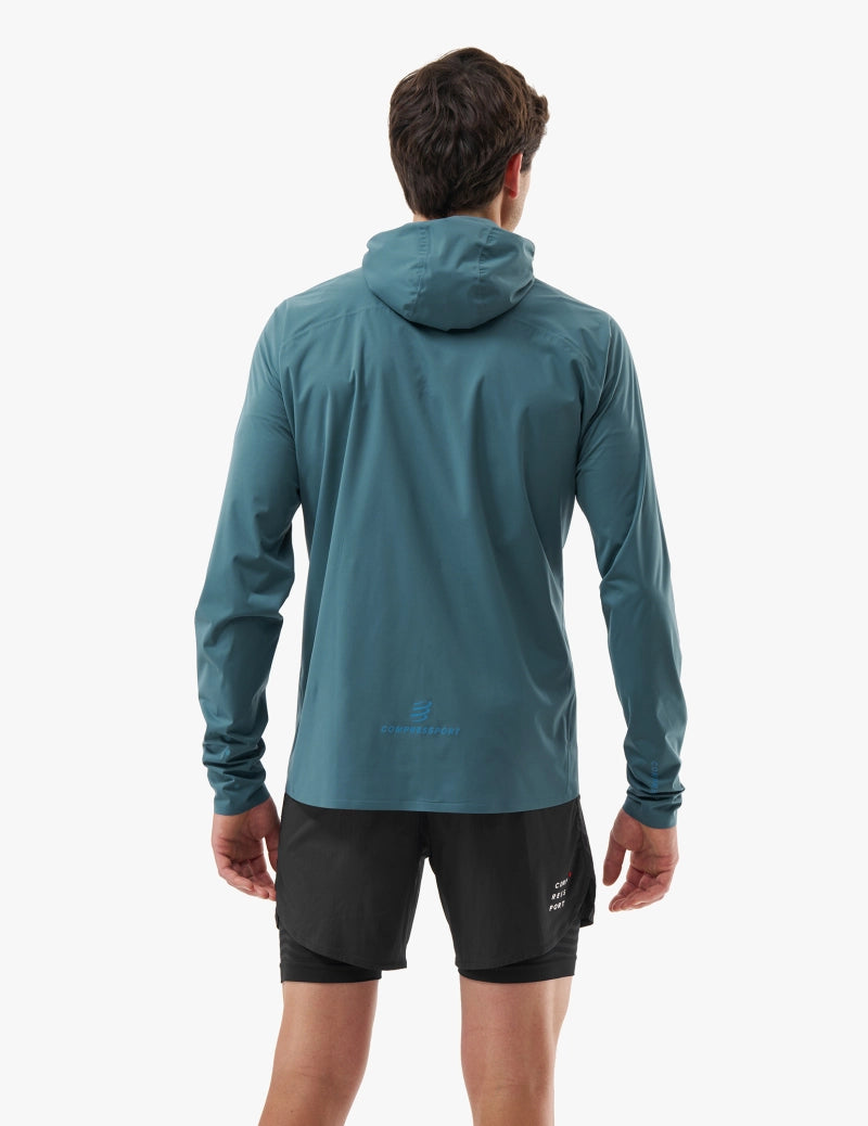 compressport tempest waterproof jacket, breathable and waterproof running jacket, deep aqua blue colour, back of jacket on male model
