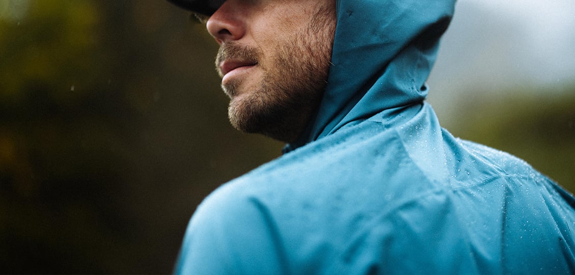 compressport tempest waterproof jacket, breathable and waterproof running jacket, deep aqua blue colour, close up of jacket material with water droplets