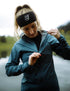 compressport tempest waterproof jacket for women, lightweight breathable and packable, dark aqua blue colour, model wearing jacket in mountains, up close model wearing jacket outside zipped open