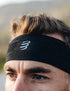 man wearing thin sports headband from compressport, in black colour with white logo