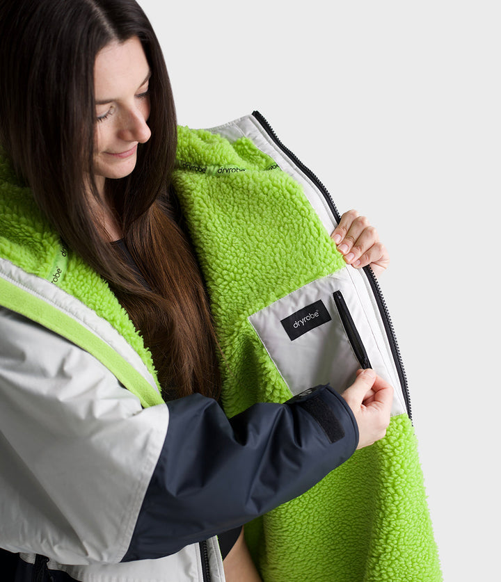dryrobe long sleeve changing robe for all gender, light grey and navy colour with lime green interior, close up of woman wearing dryrobe  showing fleece interior