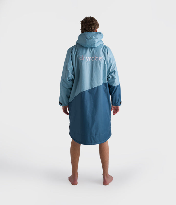 dryrobe long sleeve changing robe for all gender, light blue colour with dark blue contrast, man wearing dryrobe zipped up displaying back of dryrobe