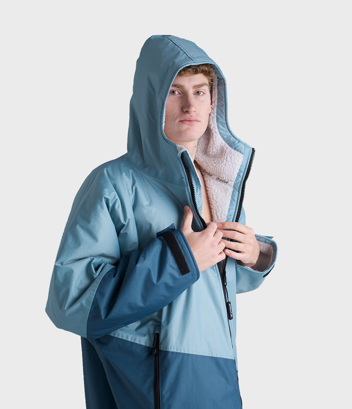 dryrobe long sleeve changing robe for all gender, light blue colour with dark blue contrast, close up of man wearing dryrobe zipped down, displaying light grey interior