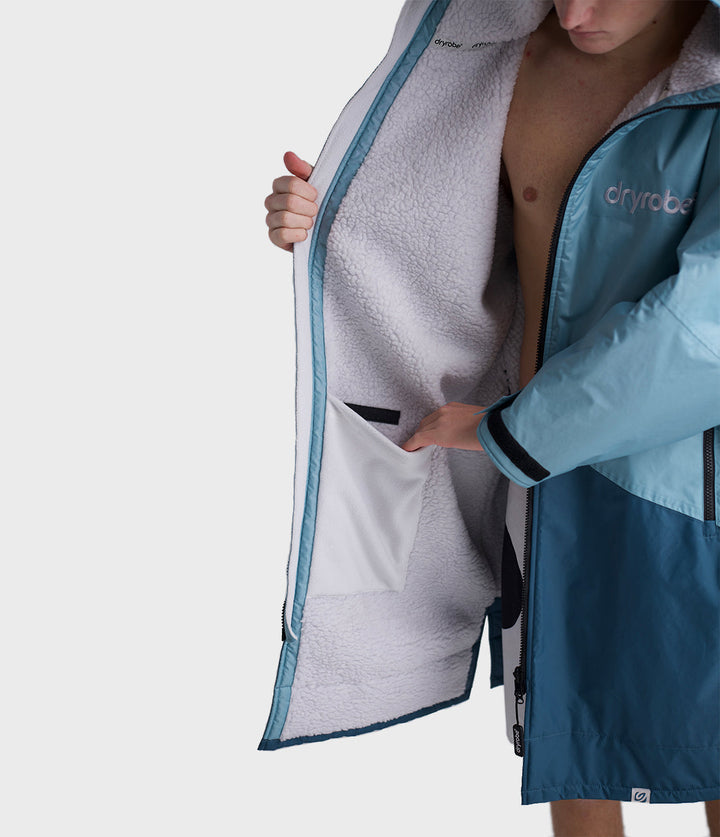 dryrobe long sleeve changing robe for all gender, light blue colour with dark blue contrast, close up of man wearing dryrobe zipped down, displaying light grey interior
