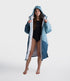 dryrobe long sleeve changing robe for all gender, light blue colour with dark blue contrast, woman wearing dryrobe zipped down, displaying light grey interior