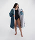 dryrobe long sleeve changing robe for all gender, light blue colour with dark blue contrast, woman wearing dryrobe zipped down, displaying light grey interior