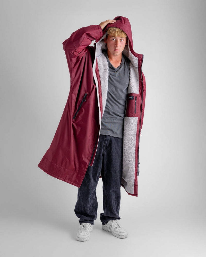 man wearing dryrobe changing robe in new burgundy colour with hood up, showing inner zip pocket