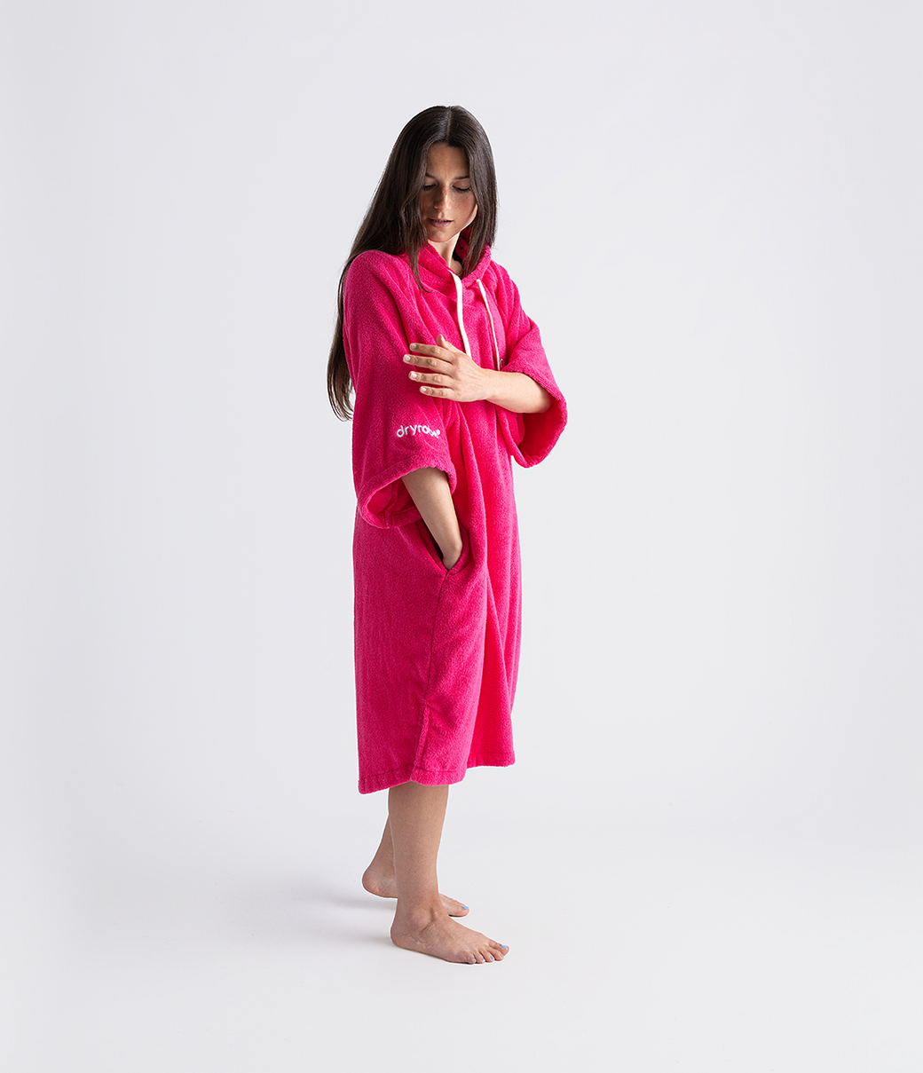 dryrobe organic cotton changing robe for swimming, soft and absorbent towelling robe for all gender, hot pink colour, woman wearing dryrobe towel on a white background
