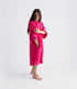 dryrobe organic cotton changing robe for swimming, soft and absorbent towelling robe for all gender, hot pink colour, woman wearing dryrobe towel on a white background