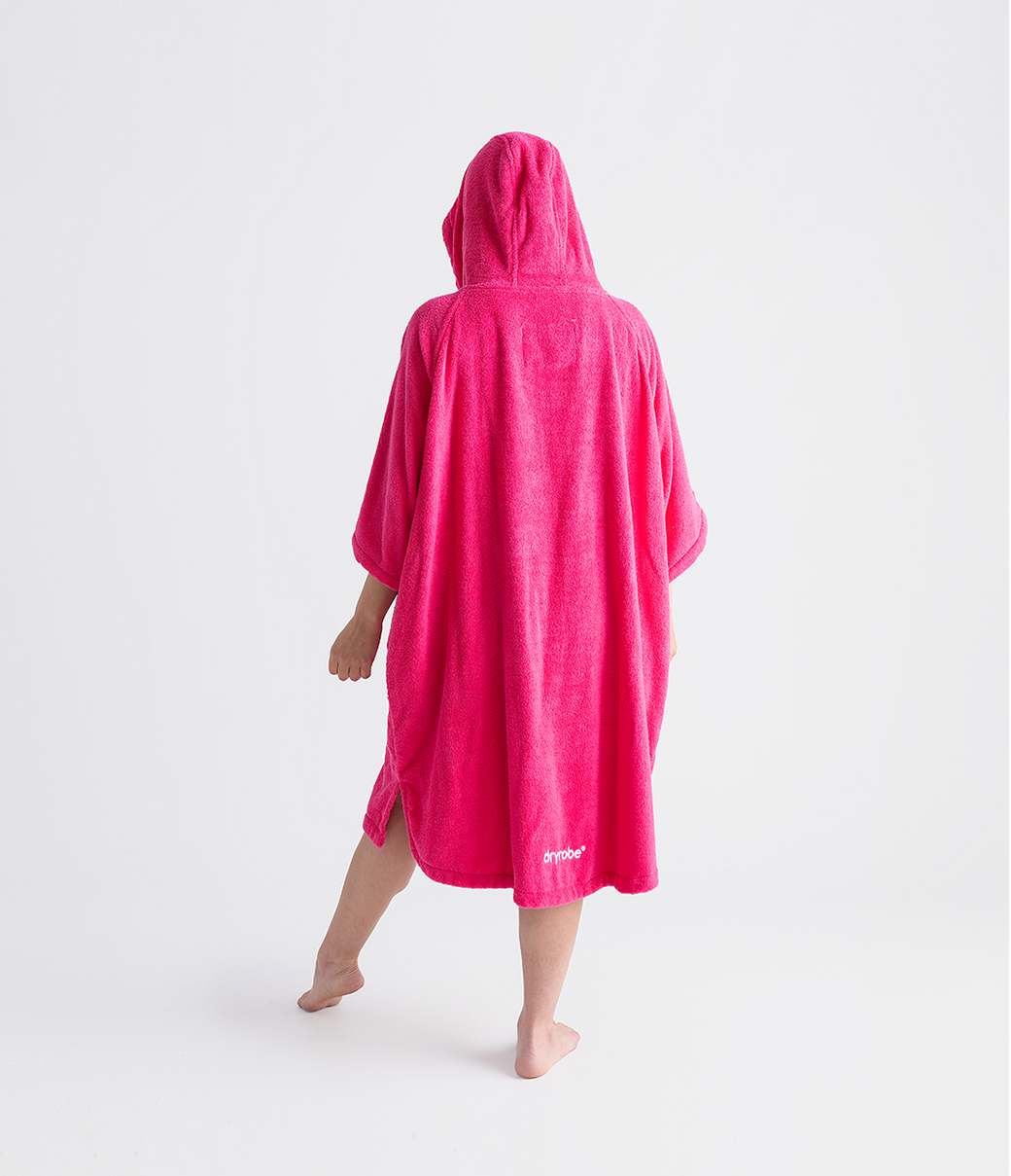 dryrobe organic cotton changing robe for swimming, soft and absorbent towelling robe for all gender, hot pink colour, back profile of woman wearing dryrobe towel on a white background