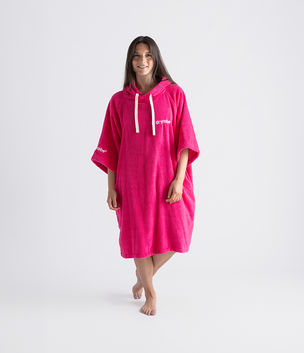 dryrobe organic cotton changing robe for swimming, soft and absorbent towelling robe for all gender, hot pink colour, woman wearing dryrobe towel on a white background
