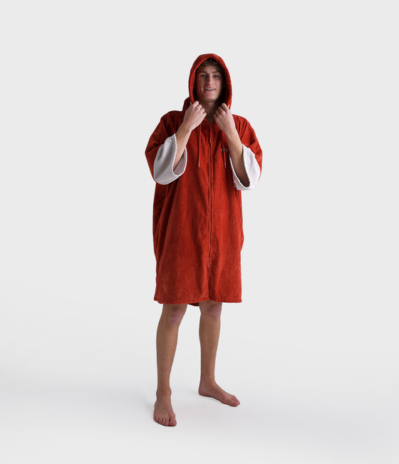 dryrobe towel robe for men and women, full zip towel robe for after swimming, dark orange colour with white sleeve caps, man wearing orange zipped up dryrobe with hood up on white background