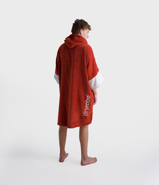 dryrobe towel robe for men and women, full zip towel robe for after swimming, dark orange colour with white sleeve caps, man wearing orange zipped up dryrobe with hood down from behind