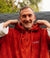dryrobe towel robe for men and women, full zip towel robe for after swimming, dark orange colour with white sleeve caps, man wearing orange zipped up dryrobe with hood down close up on top with trees in background