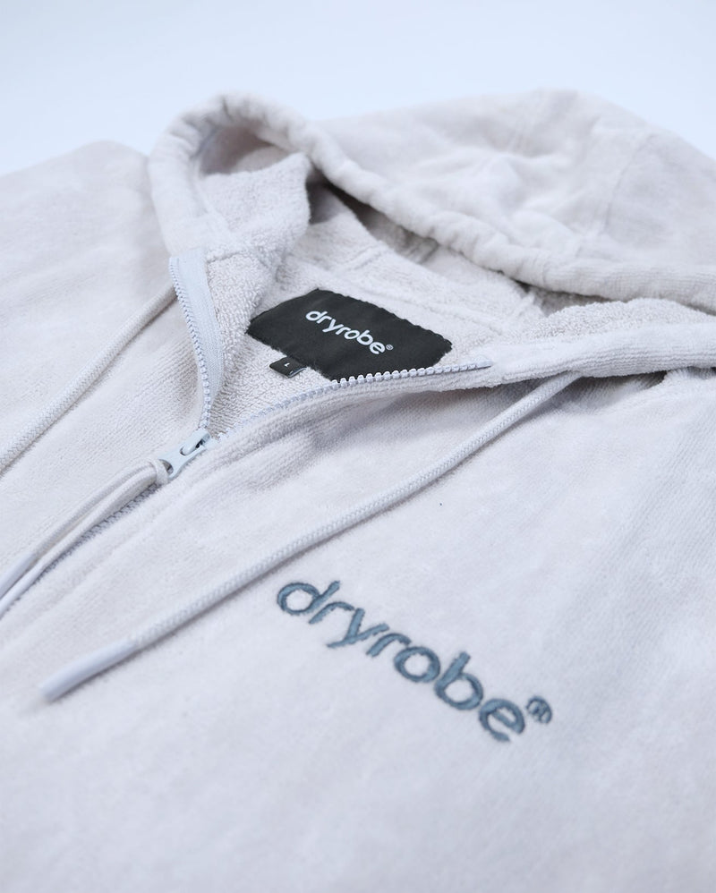 dryrobe towel robe for men and women, full zip towel robe for after swimming, light grey white colour with grey sleeve caps, close up of zipper on flat dryrobe