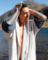 dryrobe towel robe for men and women, full zip towel robe for after swimming, light grey white colour with grey sleeve caps, man wearing dryobe outside drying off hair with hood 