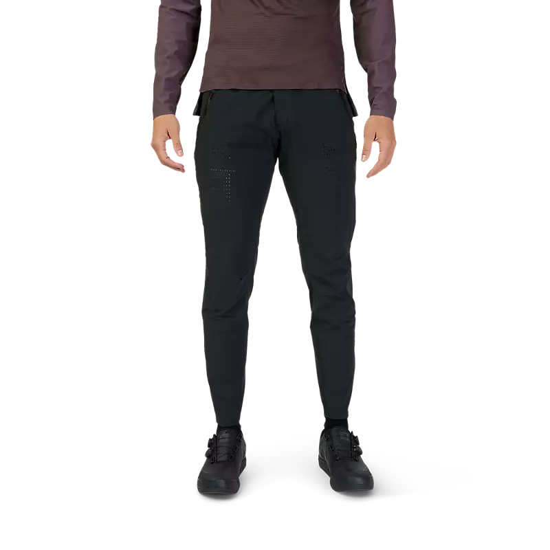 A person standing and wearing black Fox Flexair pants with a slim fit and tapered design, suitable for biking.