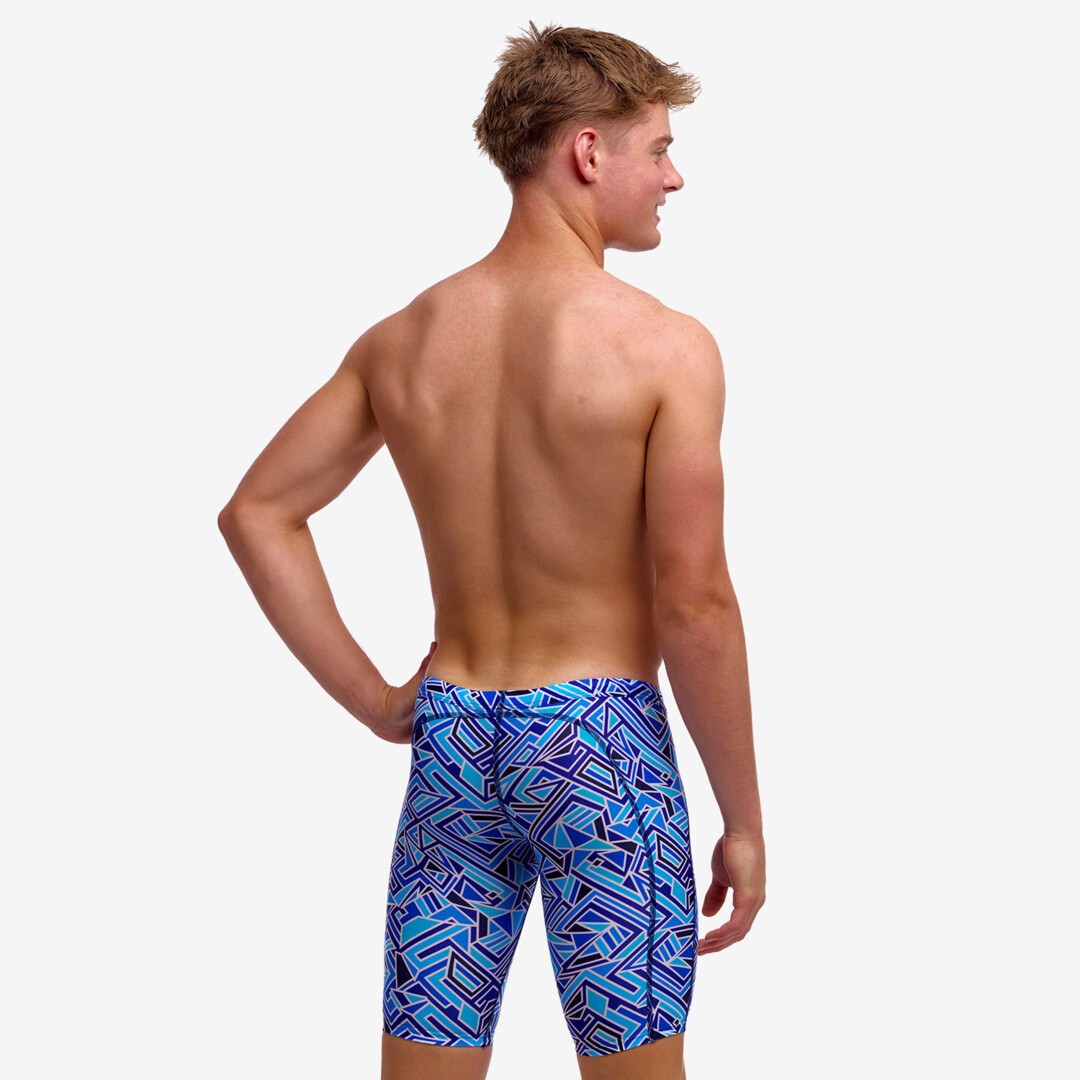 Boy wearing funky trunks jammer in blue bits pattern, showing back