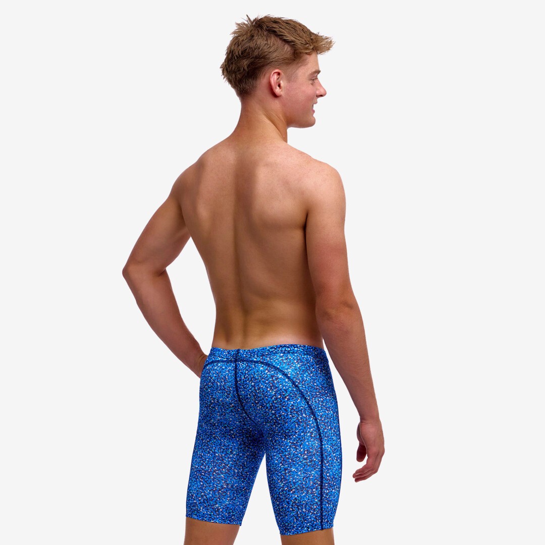 boy wearing funky trunks swim jammers in pebble beach pattern, showing back