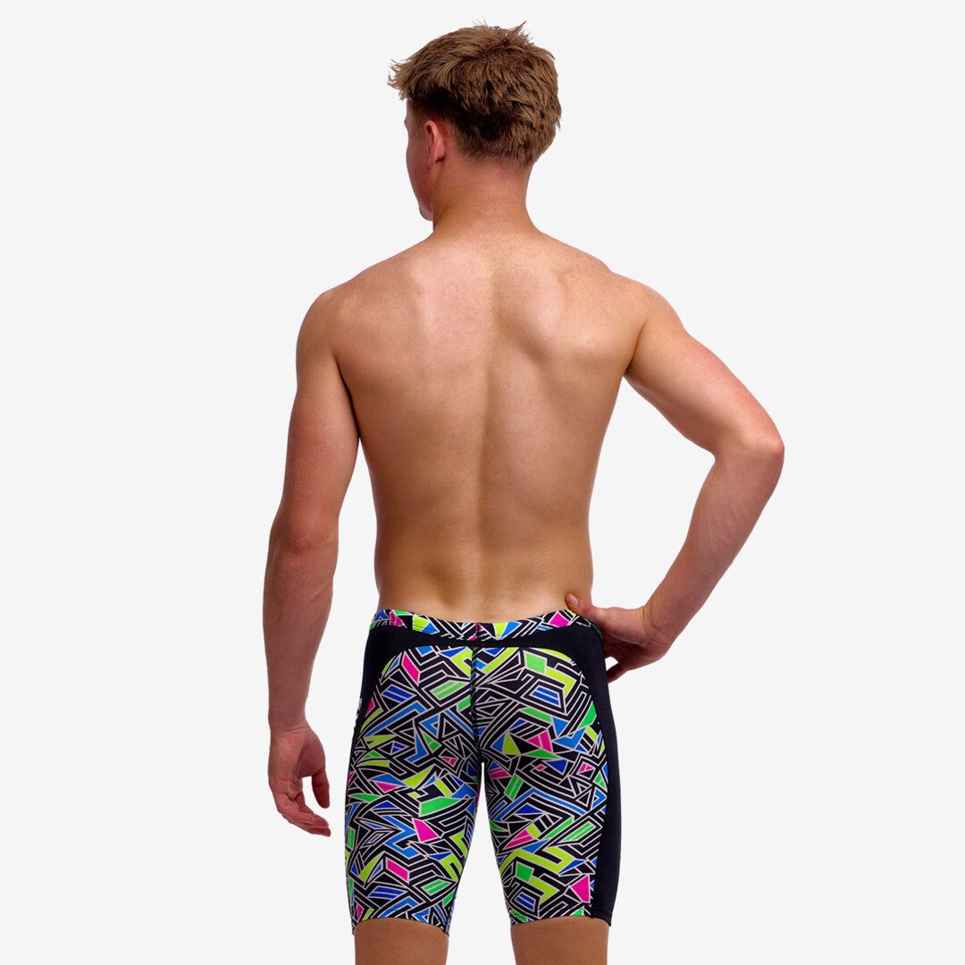 Boy wearing funky trunks jammer in bits of peace pattern, showing back