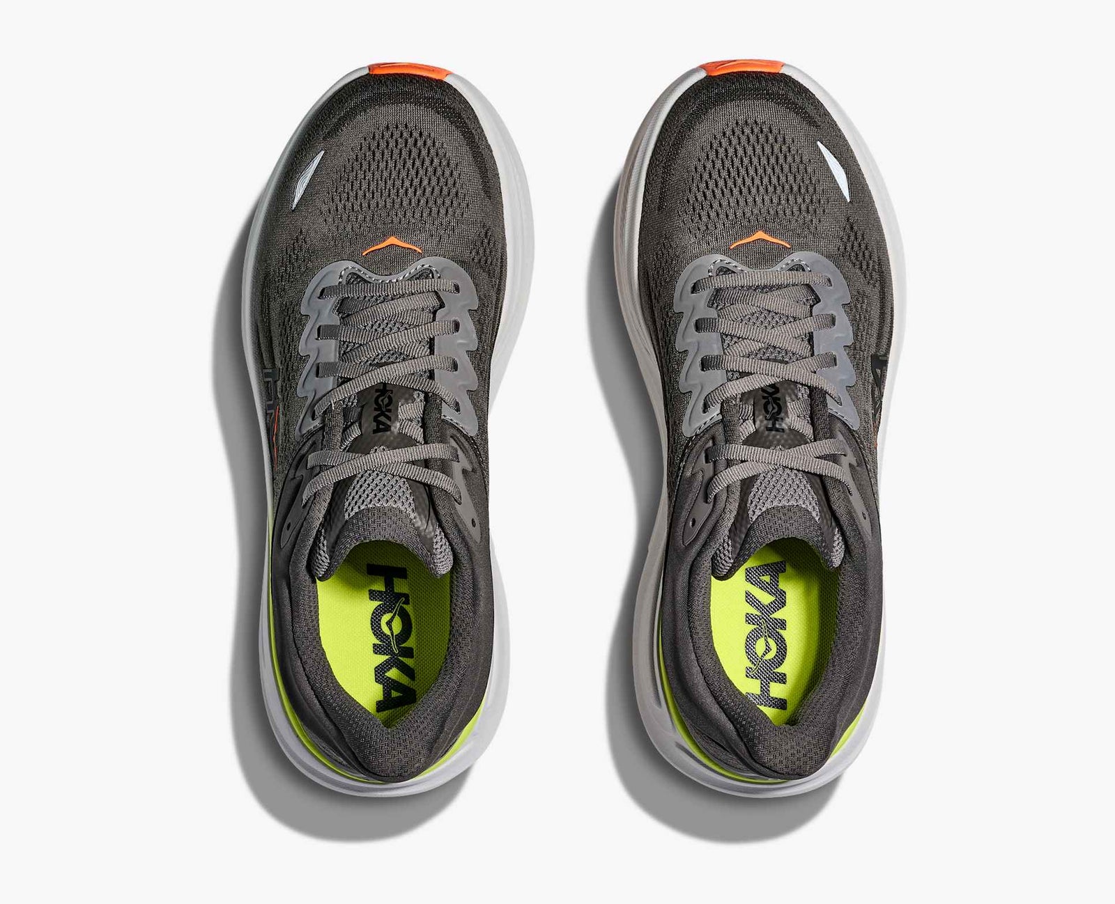 Pair of dark gray hoka bondi 9 running shoe with orange and lime green accents looking down