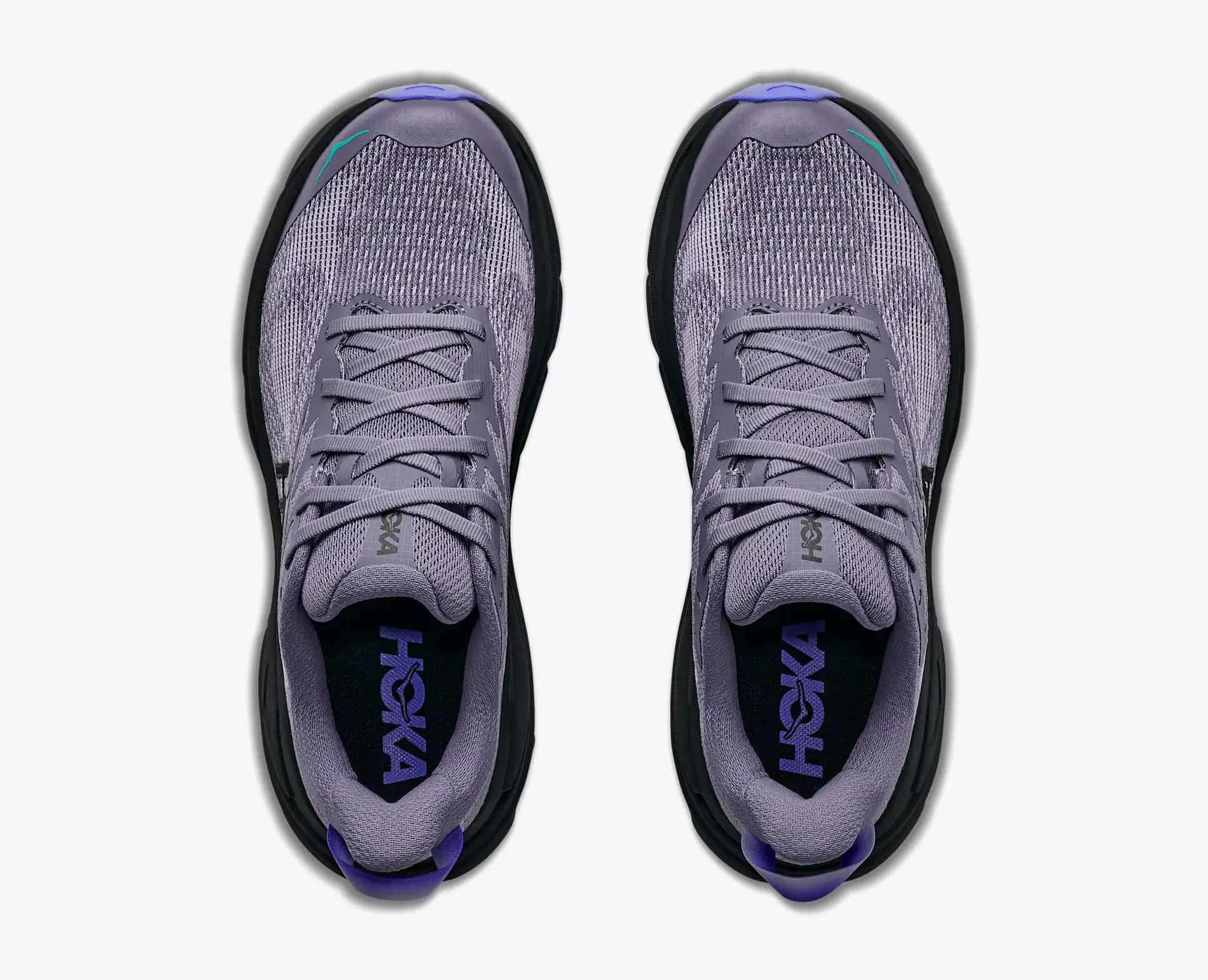 A pair of Hoka trail running shoes shown from a top-down view,light purple grey mesh upper with black soles and purple branding inside the collar.