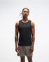 hoka everyrun tank top for men, light breathable running singlet , black colour with silver reflective HOKA logo, full body profile of a man wearing hoka tank with taupe shorts