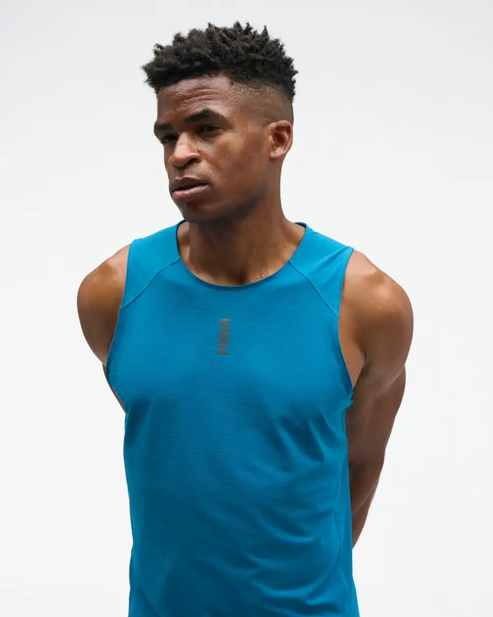 hoka everyrun tank top for men, light breathable running singlet , bright blue colour with silver reflective HOKA logo, close up of a man wearing hoka tank 
