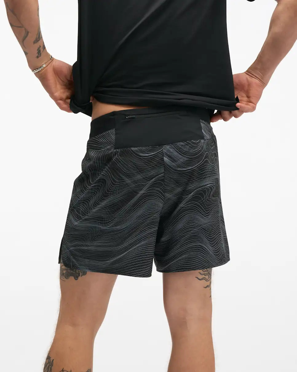 hoka 5" glide short with internal brief, black colour with white swirl pattern, back view of a man wearing hoka shorts with a black t-shirt on a white background