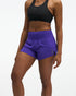Hoka glide short mr 3.5", sweat wicking trail and road running shorts with pockets, purple shorts, woman wearing black sports bra with purple shorts